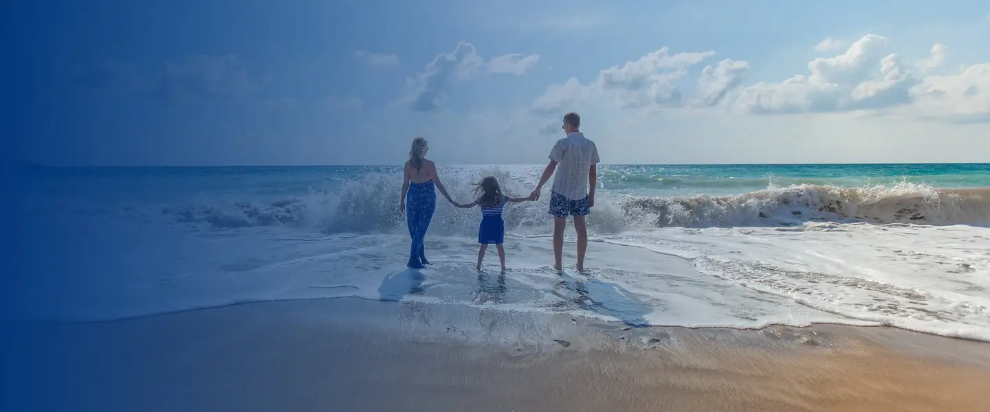 A family holding hands at the edge of the ocean